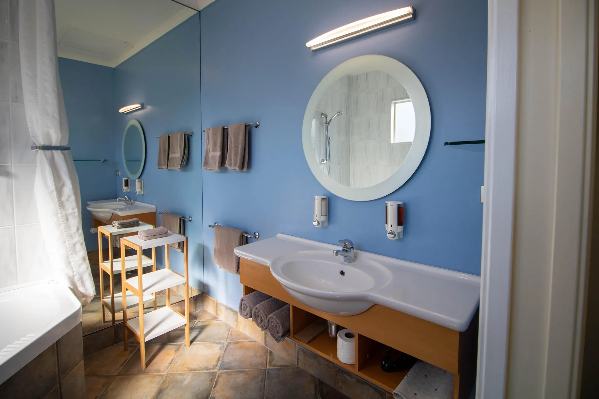 One Bedroom Unit Bathroom Vanity Bathroom vanity with round mirror, basin and towels in the one bedroom unit