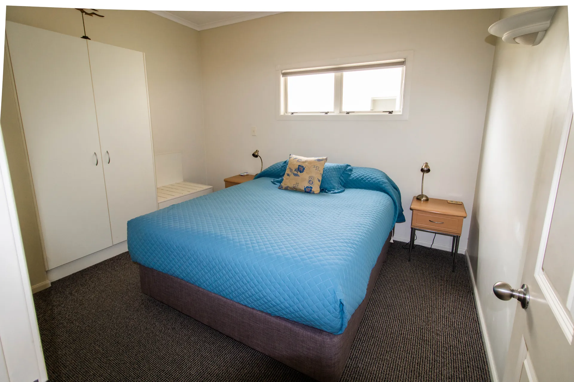One Bedroom Unit Bedroom Separate bedroom with queen bed in blue linen, wardrobe and bedside tables in the one bedroom unit