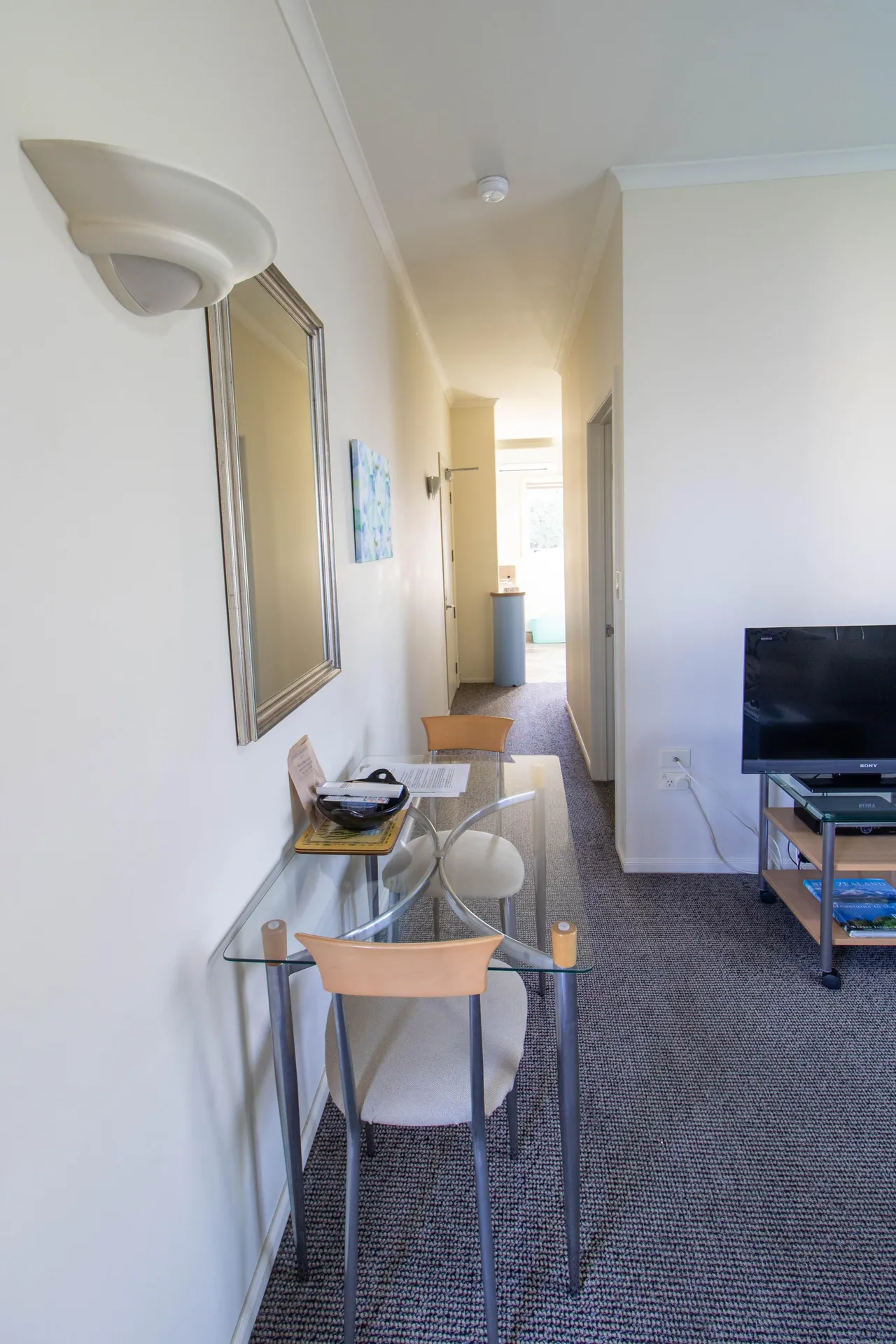 One Bedroom Unit Desk and Hallway Glass desk and hallway leading through to the bedroom and kitchenette in the one bedroom unit