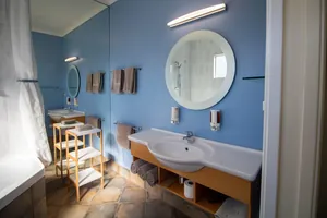 One Bedroom Unit Bathroom Vanity Bathroom vanity with round mirror, basin and towels in the one bedroom unit
