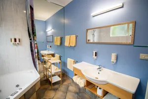 One Bedroom Unit Bathroom One bedroom unit bathroom with spa bath, vanity and towels against a blue feature wall