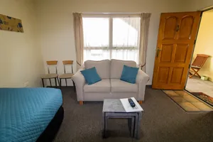 One Bedroom Unit Lounge Lounge sofa with teal cushions beside the wooden front door in the one bedroom unit