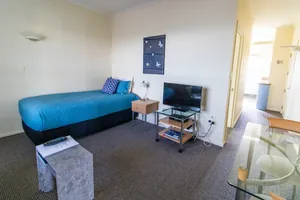One Bedroom Unit TV Area Living area with single bed, flat screen TV and glass dining table in the one bedroom unit