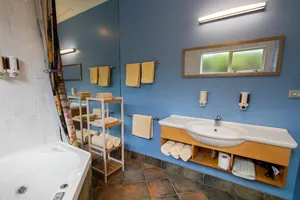 Two Bedroom Unit Bathroom Two bedroom unit bathroom with spa bath, vanity and towels against a blue feature wall