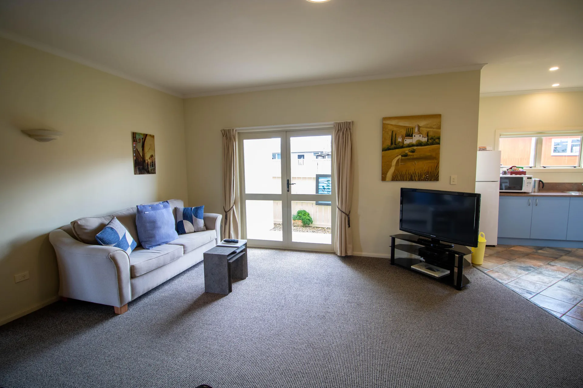 Two Bedroom Unit Lounge TV Lounge with sofa, flat screen TV and french doors opening to the courtyard in the two bedroom unit