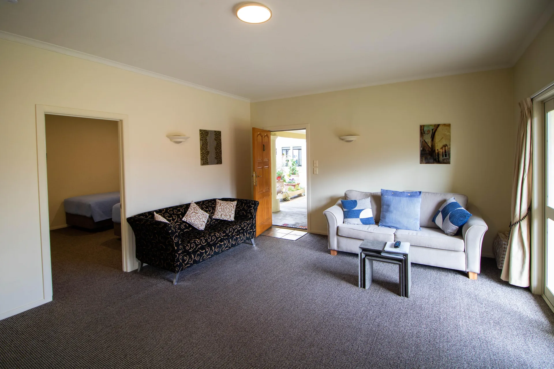 Two Bedroom Unit Lounge Two bedroom unit lounge with two sofas, artwork and the front door open to a sunny courtyard