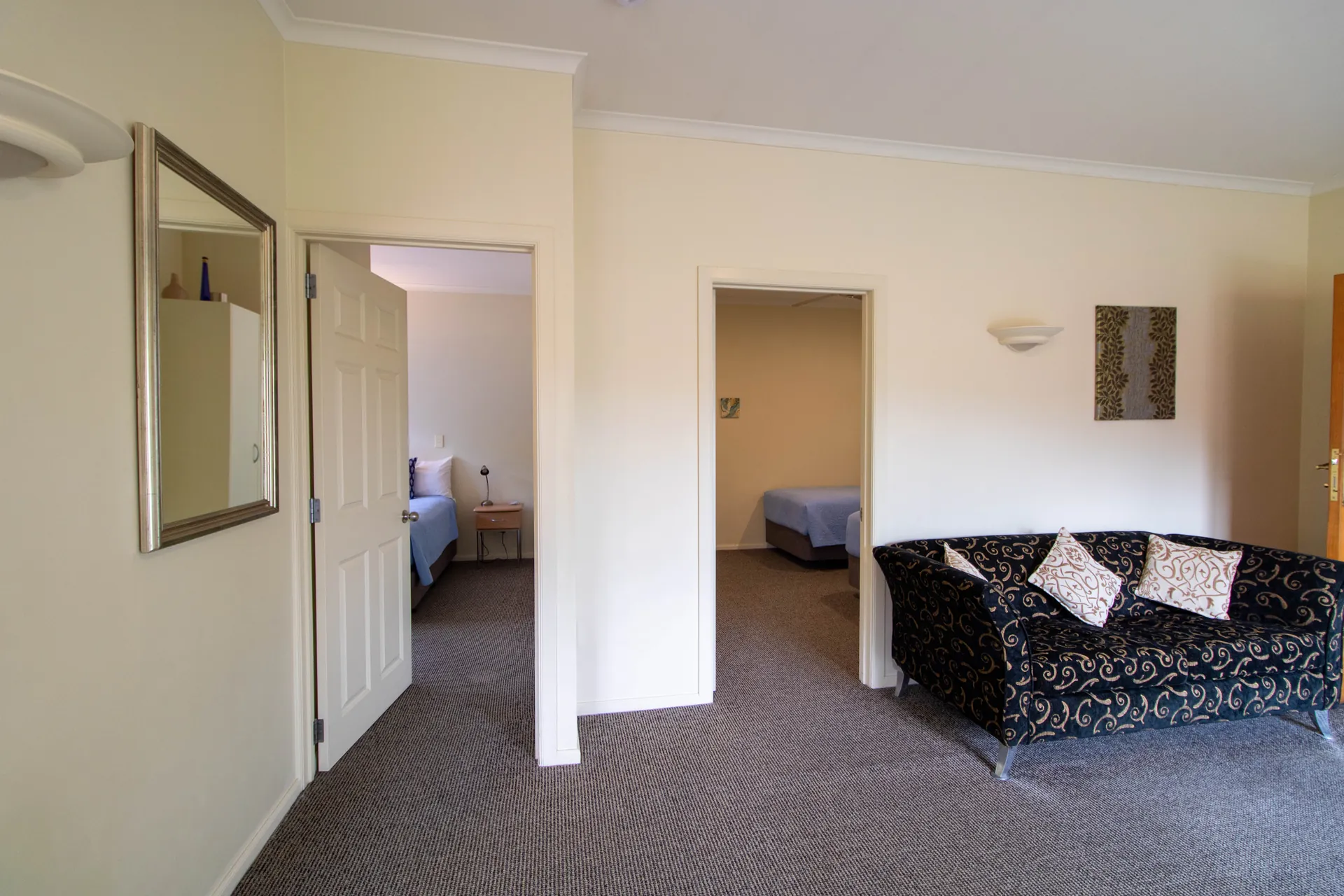 Two Bedroom Unit Two Bedrooms Hallway view showing both bedroom doorways and the lounge sofa in the two bedroom unit
