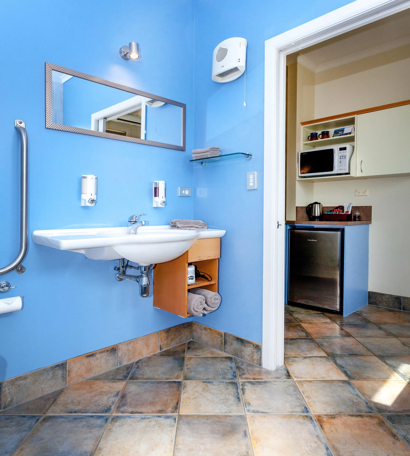 Access Studio Vanity and Kitchenette Accessible basin and mirror with view through to the kitchenette with fridge and microwave