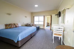 Access Studio Room Overview Access Studio with king bed, floral cushions, sofa and dining table at Tuscany on Thames