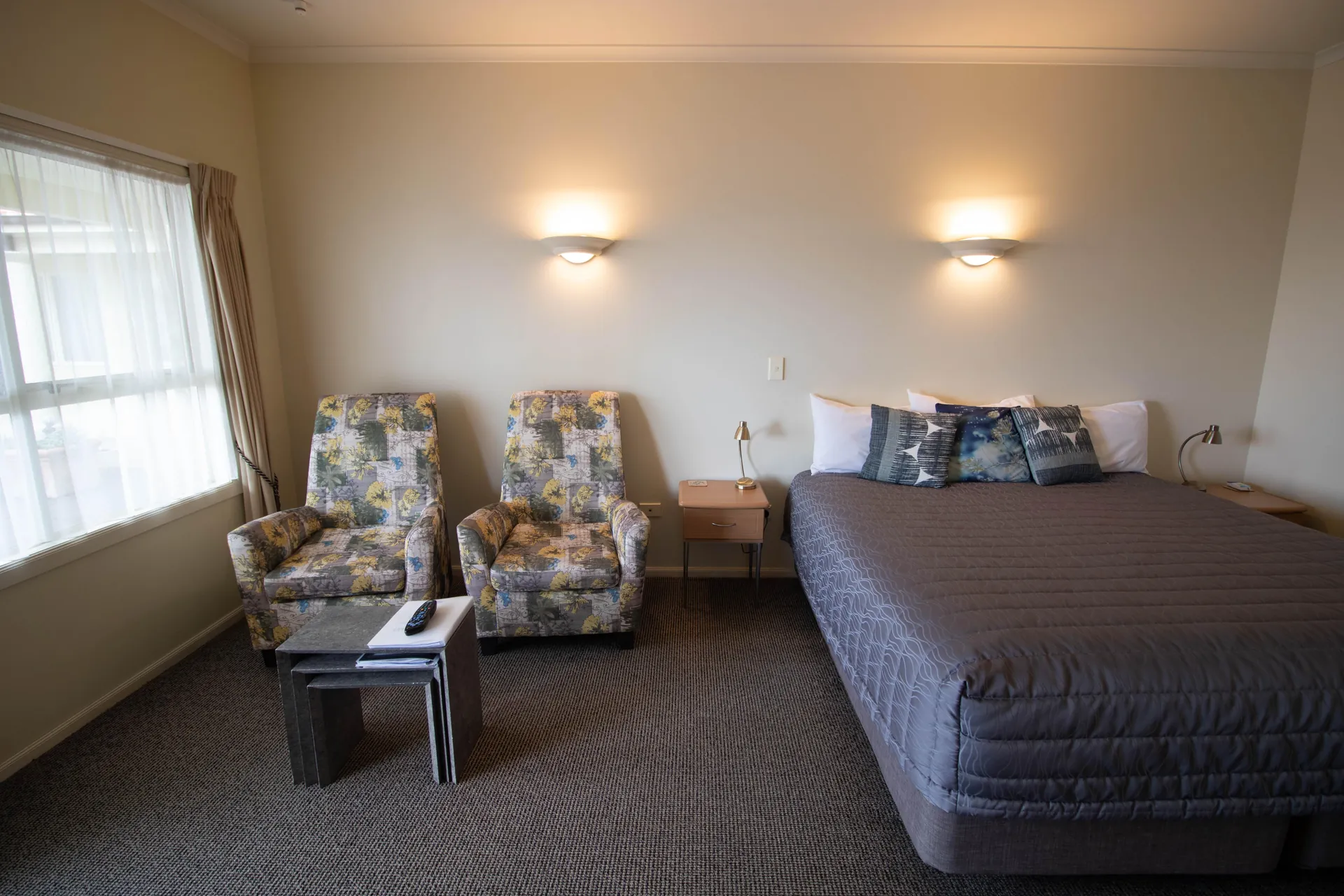 King Studio Seating Area Seating area with two floral armchairs and side tables beside the king bed and window