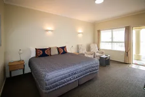 King Studio King Bed King bed with decorative cushions beside armchairs and a bright curtained window in the King Studio