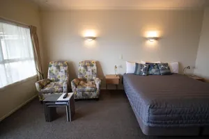 King Studio Seating Area Seating area with two floral armchairs and side tables beside the king bed and window
