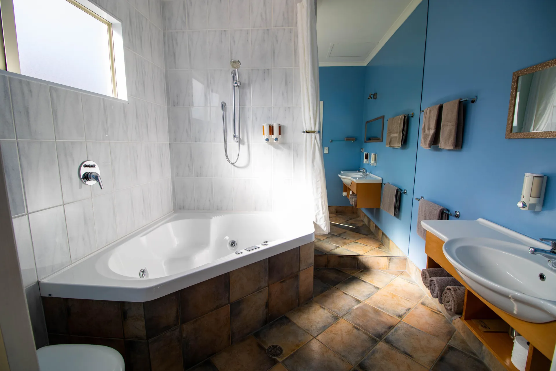 Studio Spa Bath Corner spa bath with overhead shower and terracotta tiles in the Studio bathroom